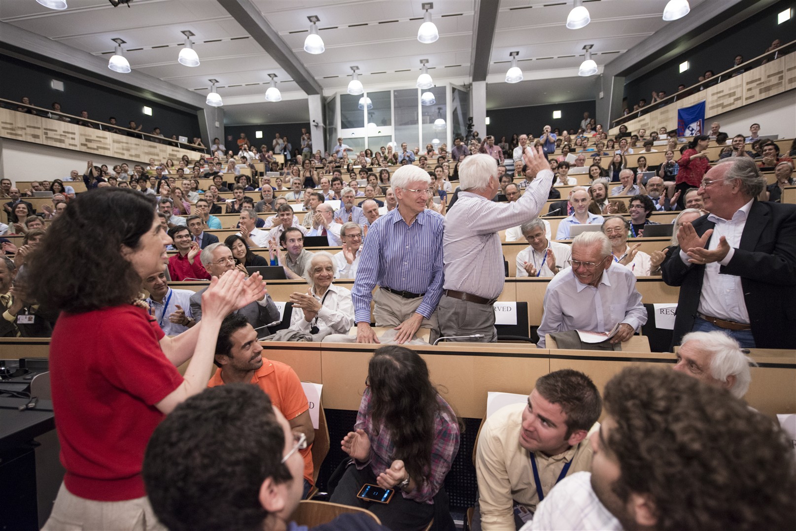 A round of applause for Fabiola Gianotti (left), ATLAS spokesperson, and Joe Incandela, CMS spokesperson, and for the LHC project leader Lyn Evans (waving), at the announcement of the discovery of the Higgs boson. 